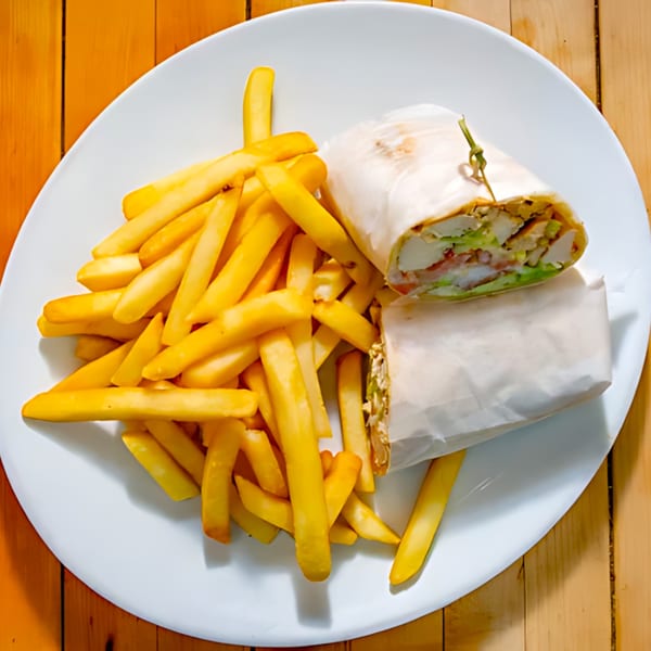 A chicken wrap, cut in half and wrapped in paper, served with a pile of golden fries.
