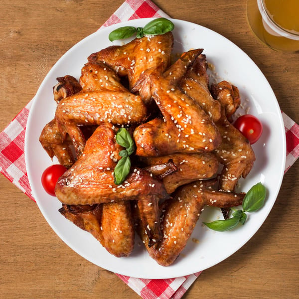 A plate of Meadowlands Diner's sesame chicken wings with cherry tomatoes and basil.